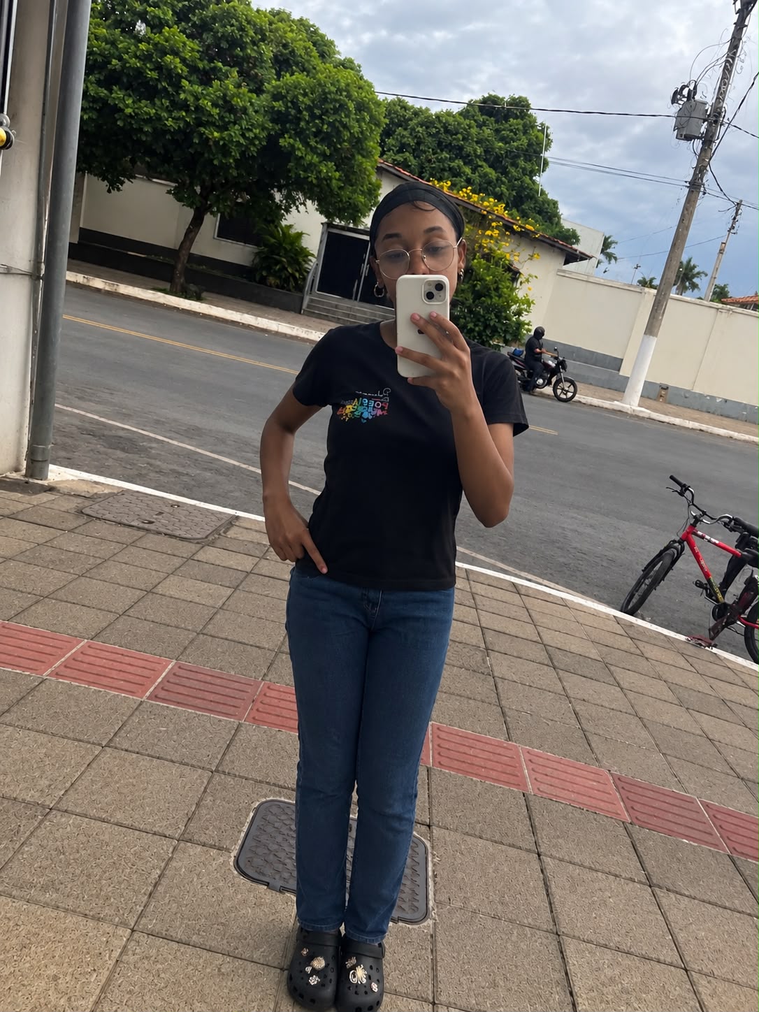 Foto de corpo inteiro de Cely usando óculos em uma calçada